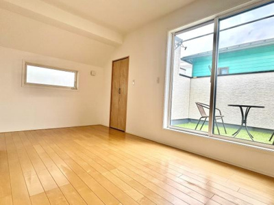 明るい日差しが差し込む洋室です。大きな窓からの開放感が魅力です。木目調の床が空間をすっきりと演出しています。バルコニーに直接出入りできるのもポイントです。