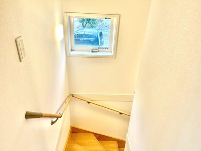 階段には窓が設置されており自然光が入りやすい仕様です。手すりが設けられており安心して昇り降りできます。シンプルな内装で明るい雰囲気が印象的です。照明も配置され夜間でも利用しやすいです。