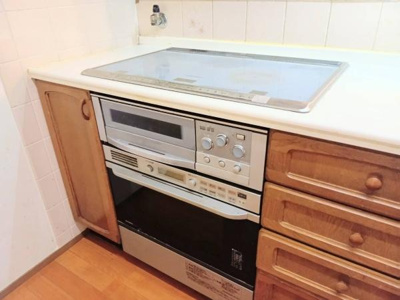 ナチュラルな木目調のキッチンが明るい雰囲気を演出しています。直線的なレイアウトで動線がすっきりしています。複数の窓があり自然光が心地よく差し込みます。レンジフードやコンロも備え付けられています。