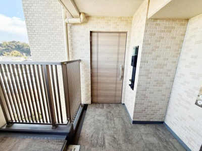 明るい印象の玄関スペースです。木目調の玄関ドアが温かみを感じさせます。レンガ調の外壁で落ち着いた雰囲気が漂います。郵便受けなどもしっかり設置されています。清潔感のある空間です。