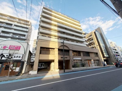 堂々とした外観が印象的な建物です。周囲には飲食店やさまざまな施設が並び利便性も感じられます。開放感のある前面道路が建物全体を明るく見せています。低層部と高層部で異なるデザインも特徴的です。