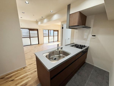 開放的なレイアウトが特徴のキッチンです。リビングやダイニングと一体感のある空間になっています。シンプルなデザインで清潔感があります。ガスコンロやレンジフードが備わっています。