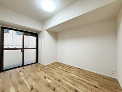 明るい光が差し込む洋室です。木目調のフローリングが温かみを感じさせます。シンプルで使いやすい空間です。大きな窓があり開放感があります。清潔感のある内装です。