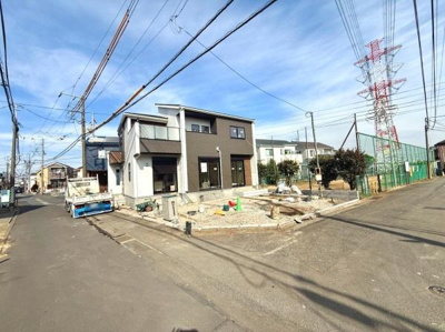 現地の様子が分かりやすい写真です。前面道路が広く車の出入りがしやすそうです。周囲には住宅や緑があり落ち着いた雰囲気が感じられます。角地で開放感があります。建築中の様子がしっかりと確認できます。