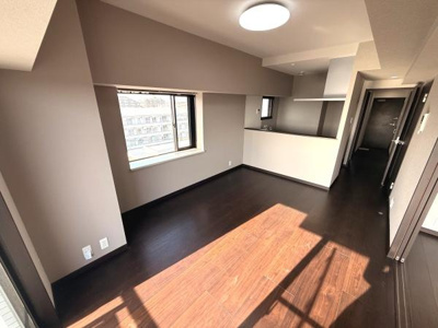 大きな窓から自然光がたっぷりと差し込むリビングです。落ち着いた色合いのフローリングが上品な雰囲気を演出しています。カウンターキッチンとの一体感も魅力です。