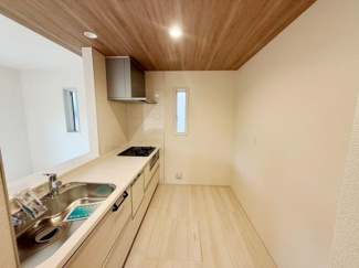 木目調の天井がアクセントになっているキッチン空間です。二面に窓があり換気に便利です。シンクとコンロが直線的に配置されており動線にも配慮されています。清潔感のあるナチュラルな色合いが印象的です。