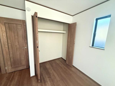 クローゼットは開口部が広く収納のしやすさが魅力です。シンプルな内装で空間がすっきりとしています。ドアの木目調が温かみを与えています。窓から自然光が入りやすいので明るい雰囲気です。