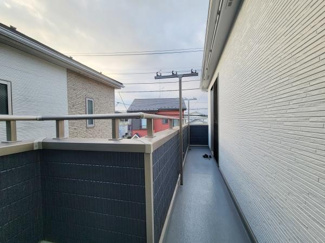 長さのあるバルコニーで日当たりと風通しが良好です。物干しスペースとしても使いやすい設計です。落ち着いた色合いの外壁が周囲との調和を感じさせます。