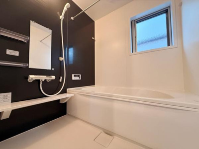 清潔感のあるバスルームです。窓から自然光が入り明るい印象です。ゆとりのある浴槽で使い勝手が良い仕様です。シャワーや棚も配置され機能性も備えています。