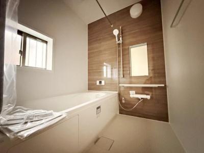 木目調パネルがアクセントのバスルームです。浴槽はゆとりのあるサイズ感で清潔感のある空間です。窓付きで換気も行いやすく快適にご利用いただけます。便利なシャワーと鏡も設置されています。