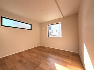 二面採光で日差しが差し込む洋室です。シンプルな内装が特徴的で空間を広く感じられます。フローリングの質感が魅力的です。窓の配置が工夫されており通風も良好です。