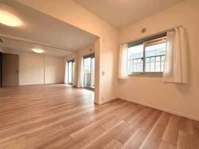 明るい色合いのフローリングが空間全体に広がり開放感のあるリビングです。大きな窓から自然光が差し込み室内をより明るく演出します。サッシやドアなどの設備も整っています。すっきりとした印象の内装が特徴です。