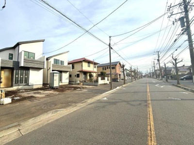 前面道路が広くゆったりとした印象を与えます。周囲には新しい住まいが並びすっきりとした街並みが広がっています。道路沿いに電柱が整然と配置されているため街全体が落ち着いた雰囲気です。