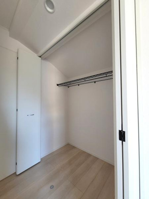 シンプルなデザインの収納スペースです。クローゼットには使いやすいハンガーラックが設置されています。扉は開閉しやすくお手入れもしやすい仕様です。床には明るい色合いのフローリングが使用されています。