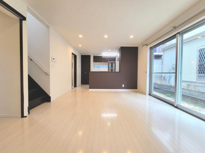 リビングには大きな窓があり明るい空間が広がります。白を基調とした床材で清潔感が感じられます。キッチンとの繋がりも良く動線が快適です。階段も近くに配置されており移動が便利です。