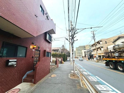 前面道路は幅員があり車両の通行もスムーズです。歩道が設けられており歩行者の安全にも配慮されています。周囲には住宅や建物が並び落ち着いた雰囲気が感じられます。