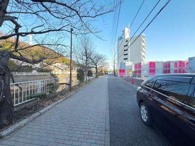 川沿いの歩道が整備されており自然を感じながら移動できます。周辺には高い建物もあり利便性も感じられます。広々とした道路が魅力で歩行や車の利用にも適しています。街路樹が季節の変化を楽しませてくれます。