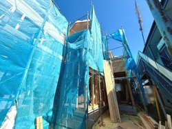 建築中の建物がしっかりとした足場で囲われており作業が順調に進んでいる様子が伺えます。ブルーシートで覆われているため工事中も安全面が確保されています。外観の構造が明確に見える貴重な状態です。