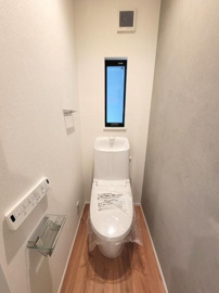 窓があり明るい空間を確保したトイレです。壁のコントロールパネルとペーパーホルダーがすっきりと設置されています。コンパクトな設計で使いやすさを追求した印象です。清潔感のある白を基調としたデザインです。