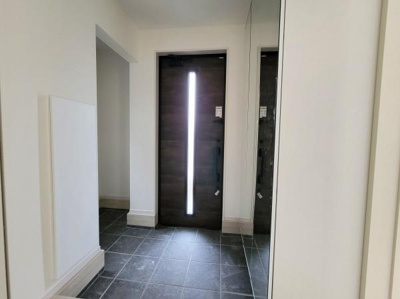 玄関の扉には縦長のスリット採光があり明るさが感じられる空間です。タイル床が清潔感を演出しています。壁や枠の色合いが落ち着いた雰囲気を与えます。広さを感じられるレイアウトです。