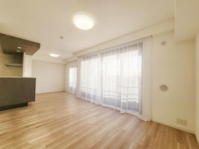 リビングには大きな窓があり明るい自然光がたっぷりと入ります。ゆとりのある空間設計で開放感があります。床は木目調で落ち着いた雰囲気を演出しています。天井にはダウンライトを配置しすっきりとした印象です。