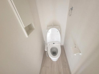 白を基調としたトイレは清潔感があります。壁面の収納スペースも便利です。床材の色味が空間に明るさをプラスしています。ペーパーホルダーやタオルリングも設置されています。