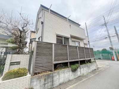 シンプルな外観が特徴的な住まいです。隣地との間にフェンスが設けられておりプライバシーが確保されています。前面道路は車両の往来が確認できる角地です。コンクリート塀と植栽もポイントです。
