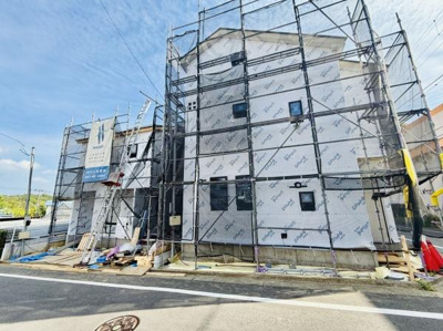 外観には工事用の足場が設置されており建築中の状態が確認できます。新築の進行状況を直接見ることができます。窓の配置なども現地で確認可能です。建物の外観全体が見渡せる写真です。