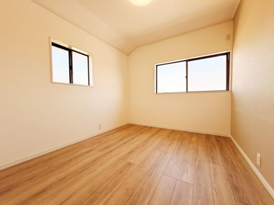 明るい光が差し込む洋室です。二面に設置された窓により室内が開放的な印象です。落ち着いた色合いのフローリングが特徴的です。壁のクロスもシンプルでさまざまなインテリアに調和します。