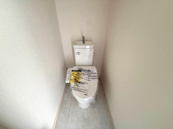 シンプルなデザインで清潔感のあるトイレです。壁や床も明るい色合いですっきりとした印象を与えます。手洗い付きタンクが設置されています。