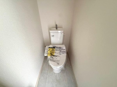 シンプルなデザインで清潔感のあるトイレです。壁や床も明るい色合いですっきりとした印象を与えます。手洗い付きタンクが設置されています。