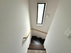 階段には縦長の窓がありしっかりとした明るさが確保されています。手すりもしっかり設置されているので移動の際も安心です。清潔感のある壁と木目の階段が調和しています。