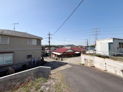 前面道路は舗装されており周辺には住宅が建ち並ぶ落ち着いた環境です。電柱の配線が空を広く感じさせ見通しも良好です。周囲には車の通行がしやすいスペースがあります。