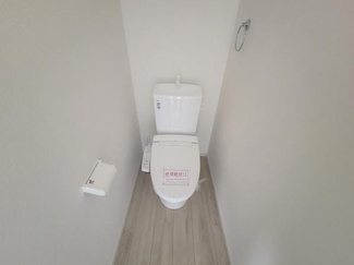白を基調としたシンプルなデザインのトイレです。床面は木目調で落ち着いた雰囲気があります。