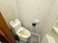 シンプルな内装で使いやすさを重視したトイレです。小窓が設けられており自然な明るさを取り入れられます。収納スペースもあり実用的なレイアウトです。壁紙と床材の組み合わせが落ち着いた雰囲気を演出しています。