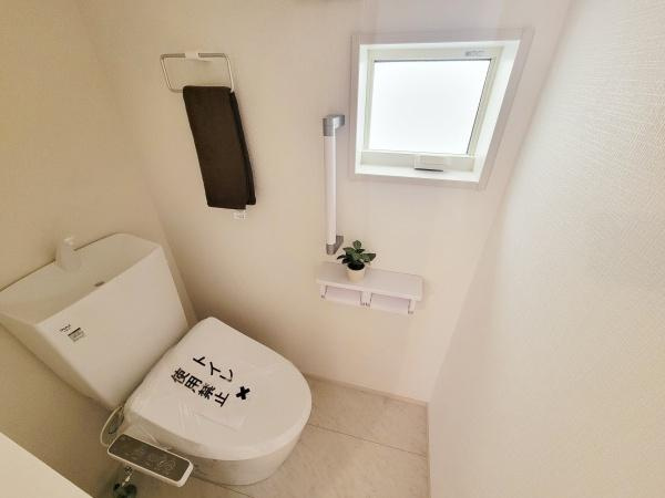 明るい空間が広がるトイレです。窓が設けられているため換気がしやすく清潔感があります。ペーパーホルダーやタオル掛けなど機能的な設備が整っています。床や壁が明るい色合いですっきりとした印象です。