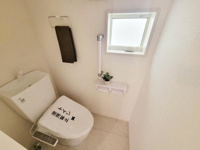 明るい空間が広がるトイレです。窓が設けられているため換気がしやすく清潔感があります。ペーパーホルダーやタオル掛けなど機能的な設備が整っています。床や壁が明るい色合いですっきりとした印象です。