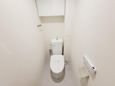 収納スペースが設けられたトイレです。すっきりとした内装で清潔感があります。壁付けのペーパーホルダーや操作パネルが設置され使い勝手にも配慮されています。広さも適度で落ち着いた雰囲気を感じられます。
