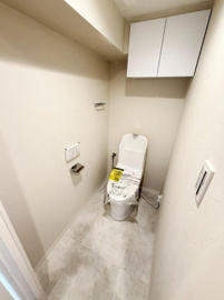 ホワイトを基調とした明るいトイレ空間です。壁付け収納が備わっており日用品の整理に便利です。床と壁の色合いが統一されているためすっきりとした印象です。手洗い付きのトイレで清潔感があります。