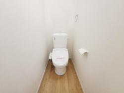 シンプルなデザインのトイレです。明るい色合いの壁と床が清潔感を演出しています。ペーパーホルダーも設置されています。空間に無駄がなく使いやすい配置です。手入れがしやすい内装となっています。