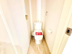 シンプルなデザインのトイレです。壁際にペーパーホルダーが設置されています。床材が明るく空間全体が清潔感のある雰囲気になっています。