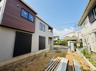 シンプルな外観デザインが印象的です。各窓にシャッターが備え付けられており安心感があります。敷地内に広がるスペースは多様な用途に活用できます。周囲は落ち着いた住宅街の環境です。