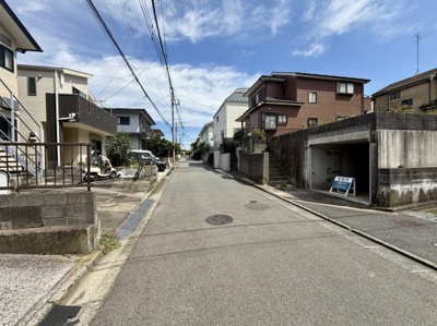 広々とした前面道路が広がり開放感を感じられる現地写真です。車通りも穏やかで落ち着いた街並みが特徴となっています。周囲の住宅も整然としており住みやすい印象を与えます。