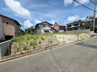 現地からは周辺住宅街の様子がよく見渡せます。前面道路は幅がしっかりと確保され車両の出入りもスムーズに行えます。写真からは現地の開放感や角地の特徴が伝わります。道路と土地の高低差も確認できます。