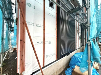 建築中の外観が分かる写真です。外壁の施工が着々と進んでいます。シャッターの設置も確認できます。建物の構造や施工状況をしっかりご覧いただけます。現場の様子が伝わる一枚です。