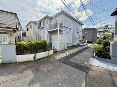 現地写真から周囲に住宅が建ち並ぶ落ち着いた街並みが感じられます。前面道路は車通りが少なく幅員も確保されています。敷地前には植栽が整えられており全体的に明るい雰囲気です。