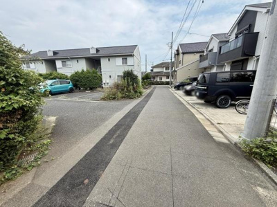 周囲には落ち着いた雰囲気の住宅が並んでいます。道路は舗装されており整然とした印象があります。駐車スペースも複数確保されています。道路幅も十分で車の出し入れも安心です。植栽も見られ緑が感じられます。