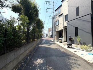前面道路はすっきりとした印象で周辺環境も落ち着いています。建物外観がシンプルで新しさを感じられます。舗装された道路が続いており毎日の出入りも安心です。植栽やフェンスも整備されている点がポイントです。