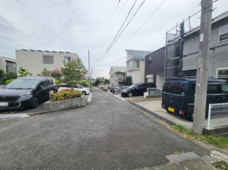 前面道路を含めた現地写真です。周辺には落ち着いた住宅が立ち並びゆとりある車の進入が可能な道路幅です。道路沿いには植栽や歩道も整備されています。現地の状況が確認しやすい写真となっています。