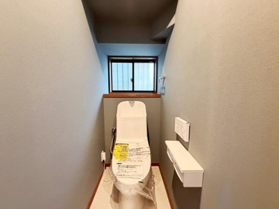 窓があり換気や採光がしやすいトイレです。清潔感のある壁紙と床材を採用しています。備え付けの収納棚が便利です。スペースに余裕があり快適に使用できます。